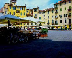 Photo by Marina T Alamanou on Unsplash The image shows the central square of the Italian town Lucca with sun umbrellas and seating places outside of restaurants.